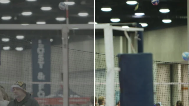 An indoor volleyball court: the left half grey, the right half with true whites and a navy pad.